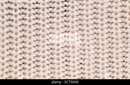 A close up of a knitted fabric with a white background. The fabric is made of yarn and has a very intricate pattern. Concept of warmth and comfort Stock Photo