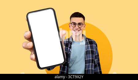 Young Man Showcasing a Smartphone Against a Bright Yellow Background in an Engaging Montage Scene Stock Photo