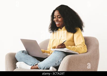 Cheerful african-american woman attending webinar, using laptop Stock Photo