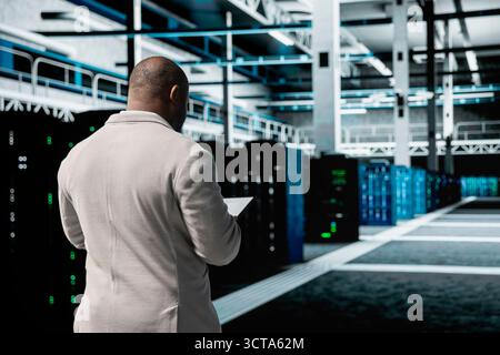 Technician in data center workspace running system diagnostic tests, increasing uptime and efficiency. Employee looking for network issues affecting rigs performance, installing upgraded server racks Stock Photo