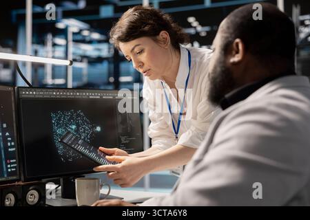 Data center engineers collaborating, doing brainstorming, analyzing software logs to optimize storage systems. Server farm teamworking colleagues inspecting resource utilization on device Stock Photo