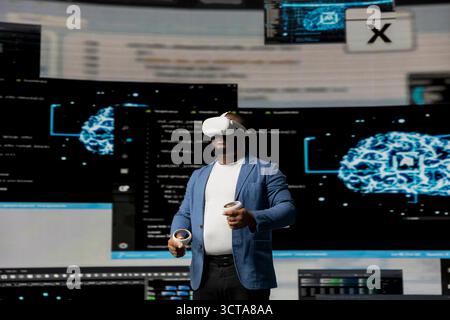 African american software technician uses virtual reality glasses and codes, high tech interface environment. Surrounded by terminal windows, represents digital workspace culture. Stock Photo