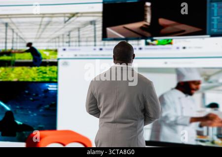 Man facing digital video wall, benefiting from endless entertainment selection. Viewer enjoying access to various streaming options, looking at screens displaying movies and TV shows clips Stock Photo