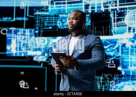 Young black technician reviewing AI data visualization and neural networks platforms, smart technology cyberspace systems. Studies machine learning, cloud computing and algorithms. Stock Photo
