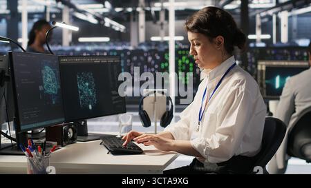 Cheerful data center engineers dancing in excitement in office chairs after successful AI deployment. Smiling server room colleagues celebrating achievement, reaching performance goals, camera A Stock Photo