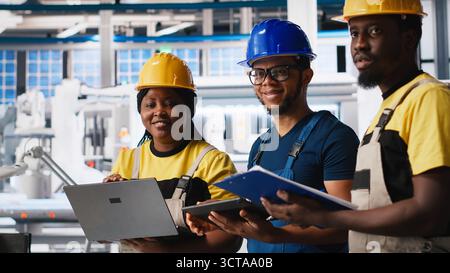 Solar panels engineers team developing new photovoltaic materials using devices in the manufacturing plant. Black workers group conducting experiments for better production line. Camera A. Stock Photo