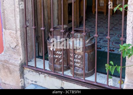 Two old metal cans with the words "Fashioned from the finest raw materials" written on them. Historic center of Queretaro, colonial architecture, deco Stock Photo