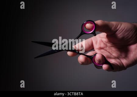 Barber scissors in hands. Barbershop. Barbershop advertising. Man holding Barber scissors. Barber scissors, barbershop. Mans haircut in barber shop. Stock Photo