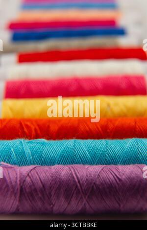 A collection of vibrant spools of thread in various colors lined up neatly on a table, perfect for sewing enthusiasts or craft projects in a creative Stock Photo