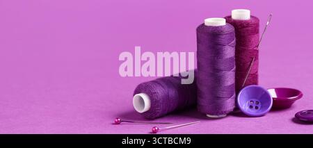 Spools of threads and sewing supplies on purple background with space for text Stock Photo