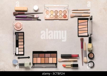 Frame made of makeup brushes and cosmetic products on beige grunge background Stock Photo