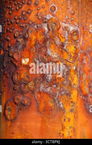 Heavily rusted steel post corroded by years of exposure to sea water, showcasing the effects of marine erosion and saltwater decay. Stock Photo
