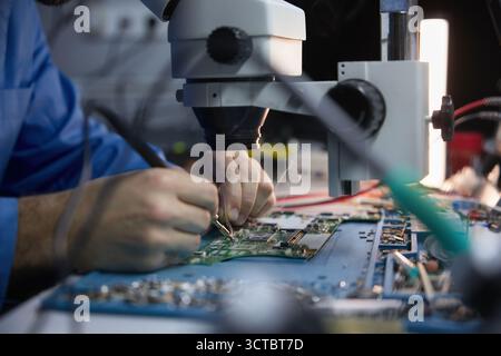 Technician repairing circuit board under microscope Stock Photo