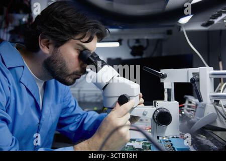 A scientist is examining samples under a microscope in a well-equipped lab for research Stock Photo