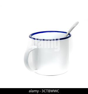 Empty white enamel cup with blue rim and spoon isolated on white background Stock Photo