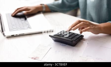 Hands of female accountant typing on calculator and laptop Stock Photo