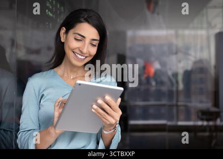 Positive young Latin coach woman using tablet Stock Photo
