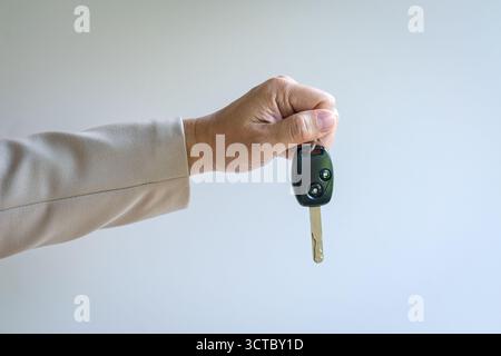 Man holding a car key, isolated on white background. Stock Photo