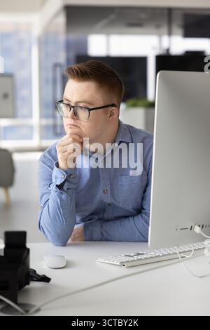 Thoughtful creative professional with Down syndrome thinking on ideas Stock Photo