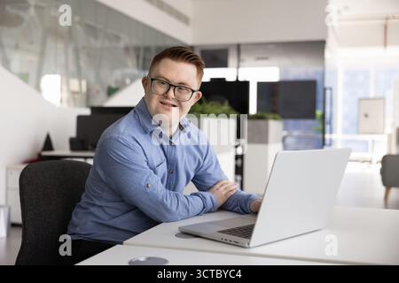 Positive Caucasian business professional man with Down syndrome using laptop Stock Photo