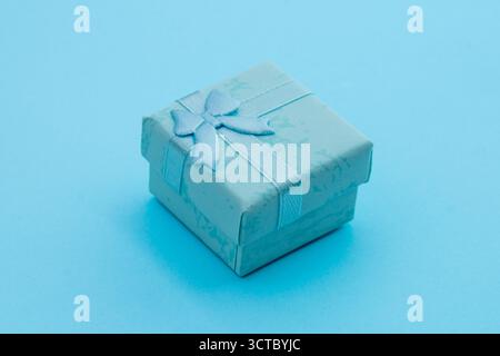 A clean minimalist of a small square gift box presented on a seamless light blue background. Giving, special occasions, surprises, jewelry, and celebr Stock Photo