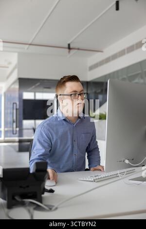 Busy designer man with Down syndrome working on online product Stock Photo