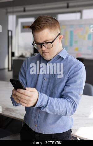 Focused male employee with Down syndrome using Internet technology Stock Photo