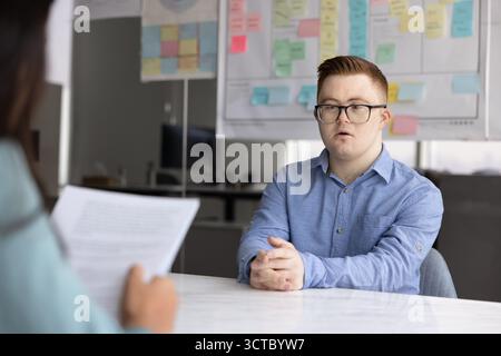 Young male job candidate with Down syndrome talking to recruiter Stock Photo