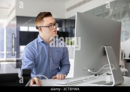 Serious professional man with Down syndrome working on business project Stock Photo