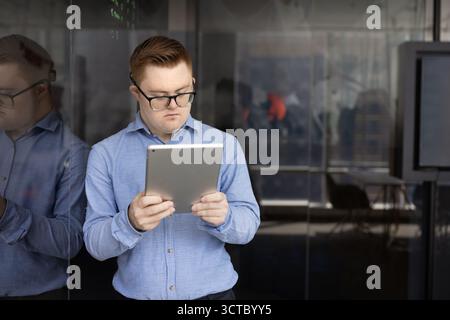 Focused male inclusive company worker with disability using tablet Stock Photo