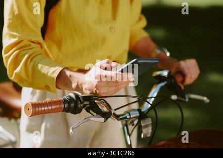 Young Adult Caucasian Woman Using Smartphone While Standing with Bicycle Outdoors Stock Photo