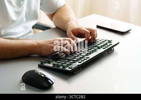 Typing on a modern keyboard while using a computer mouse in a bright office setting Stock Photo