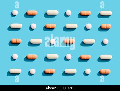 Pills and capsules arranged in a grid pattern on a bright blue background, representing health, medicine, and wellness Stock Photo