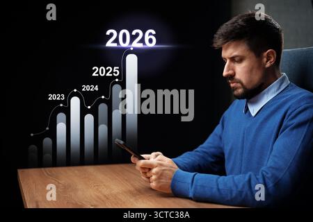 Man analyzing growth charts on smartphone with projections through 2026 Stock Photo