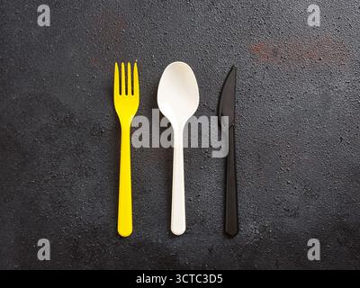 Brightly colored plastic fork, spoon, and knife arranged in a row, representing fast food, single use, and to go dining Stock Photo