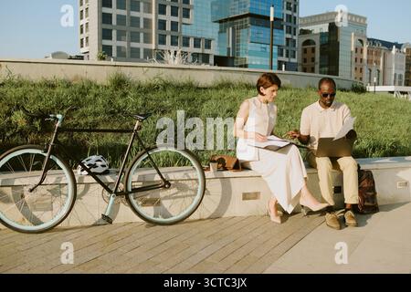 Young Caucasian Woman and Young Black Man Collaborating Outdoors with Laptop Stock Photo
