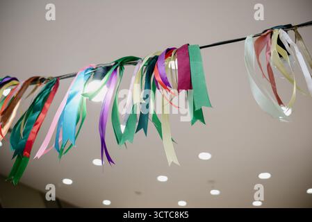 Multicolored ribbons and a garland of light bulbs under the ceiling for a festive interior decoration. Stock Photo