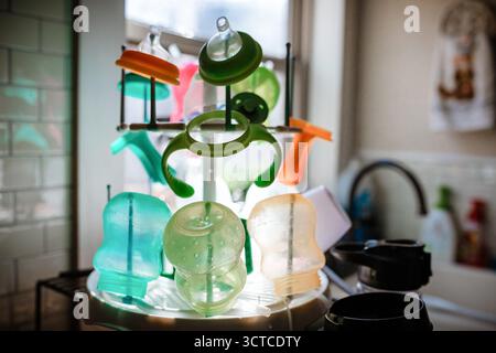 Colorful sippy cups on drying rack in kitchen Stock Photo
