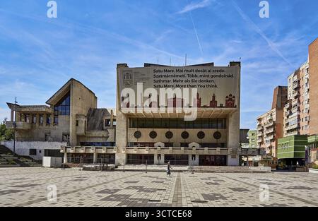 Modern building with a large billboard in an urban setting under a blue sky.cultural centre in Satu Mare Romania Stock Photo
