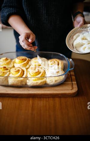 Spreading frosting on cinnamon rolls Stock Photo