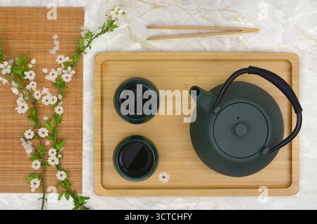 Classic sakura - blooming cherries and tea in cups, green kettle on a tray. Top view photo mixed with graphics, ascetic and simple. Stock Photo