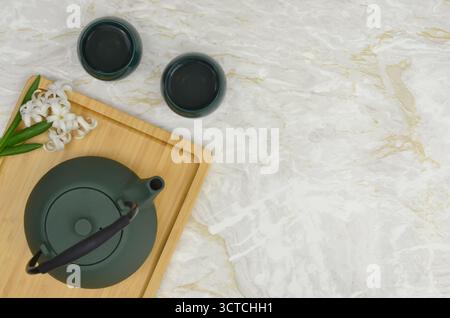Sakura, tea time, simple and elegant table decoration with empty space to fill with content. Green cast iron tea pot and two cups, wooden tray. Stock Photo