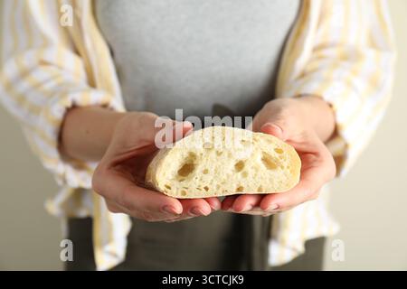 Woman holding half of fresh ciabatta on light background, closeup Stock Photo