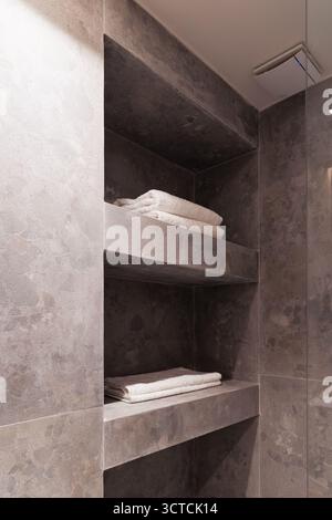 Modern bathroom vanity featuring a natural stone basin, wood shelf, and a mirror. A hair dryer hangs nearby, suggesting full amenities Stock Photo
