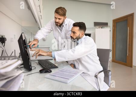 Two medical professionals in white lab coats collaborating at computer Stock Photo