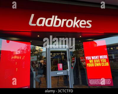 Manchester, UK - September 25, 2025: Bright betting shop exterior with red branding and glass doors, promotional poster visible. Stock Photo