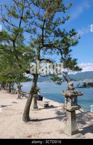 Japan: stone lanterns lining the promenade of the main beach on Miyajima Island (the name often given to Itsukushima Island) located in Hiroshima Bay Stock Photo