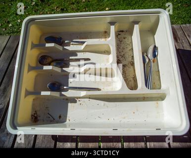 a messy drawer with silverware on the table needs to be cleaned Stock Photo