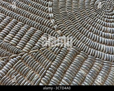 Spiral Pattern Pebble Mosaic Pavement - Intricate design of tightly packed gray river stones forming a radiating spiral mosaic pavement. Stock Photo