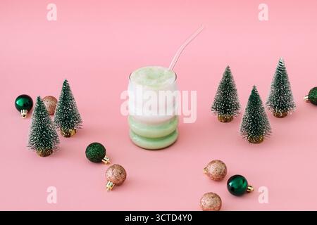 Christmas composition with matcha latte and Xmas trees and decorations on pastel pink background. Minimal Christmas and New Year concept. Stock Photo